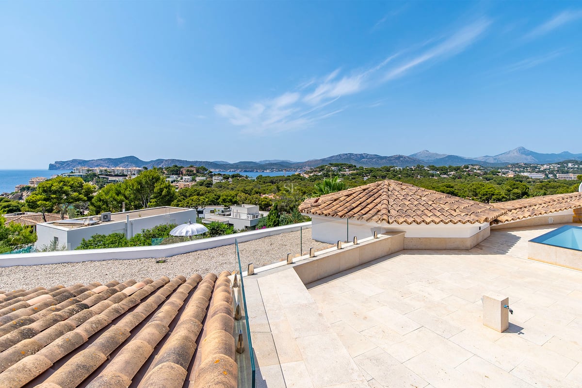 Extérieur d'une villa moderne avec piscine, grandes fenêtres et design minimaliste. Jardin luxuriant et ciel bleu.