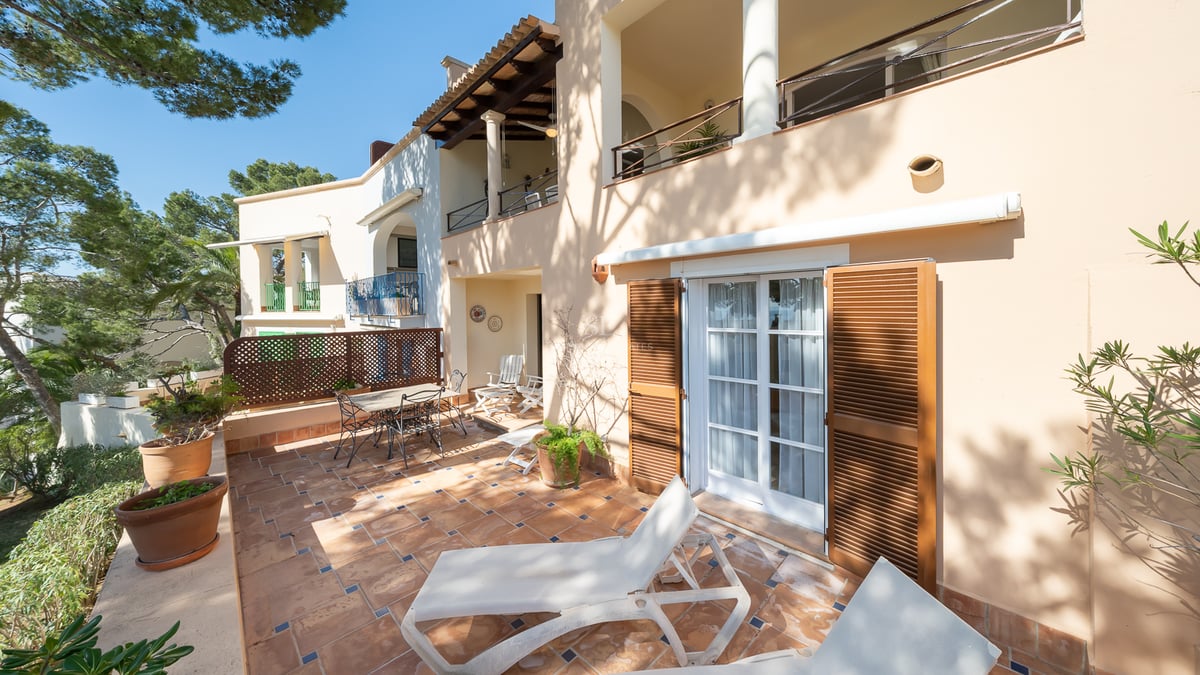 Terrasse ensoleillée avec carrelage en terre cuite, chaises longues blanches et coin repas extérieur.