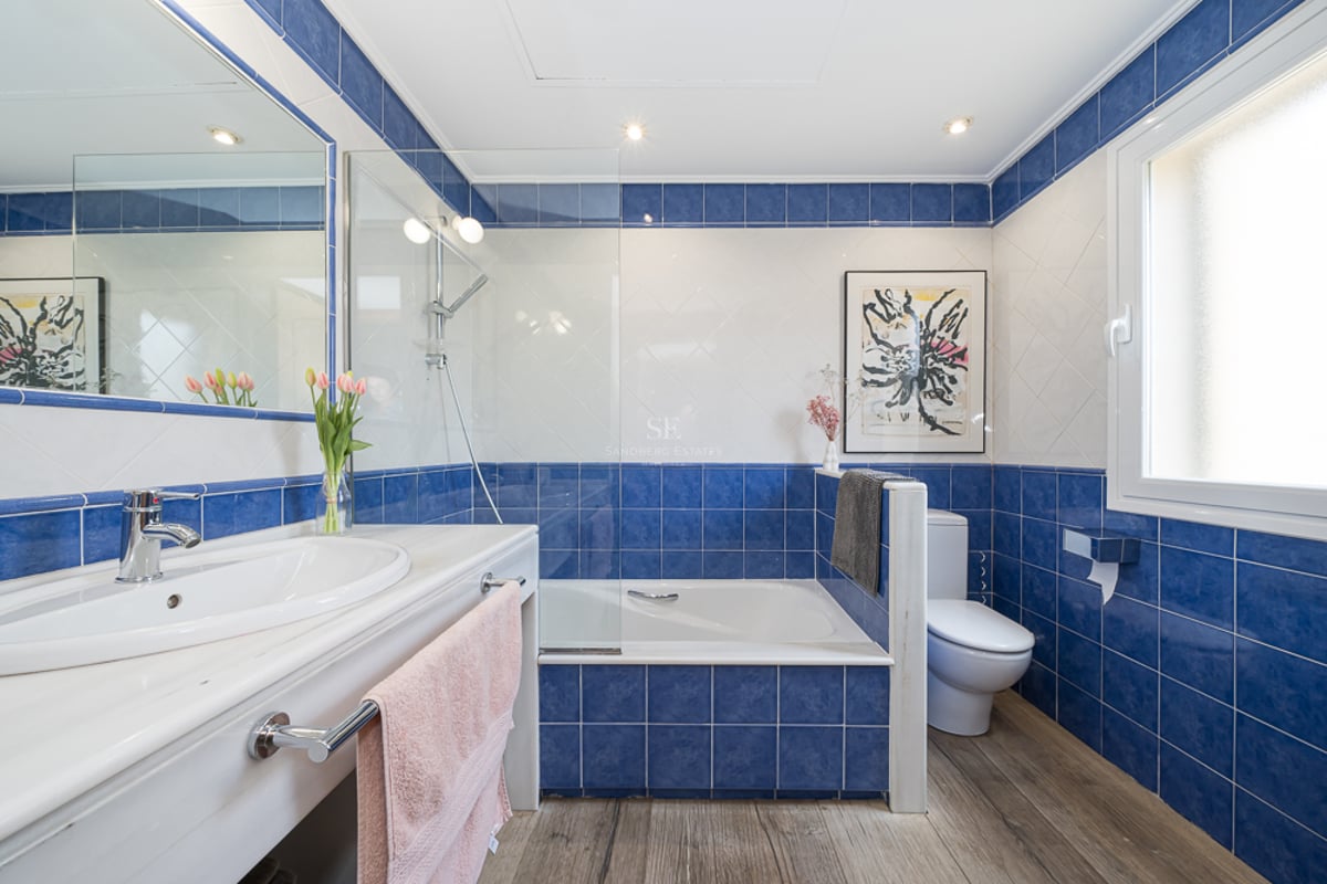Salle de bain contemporaine avec carrelage bleu cobalt et blanc, plan de toilette en marbre et baignoire avec paroi en verre.