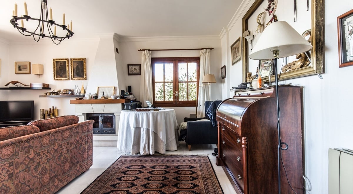 Salon chaleureux avec canapé à motifs, cheminée, tapis d'Orient et secrétaire en bois ancien.