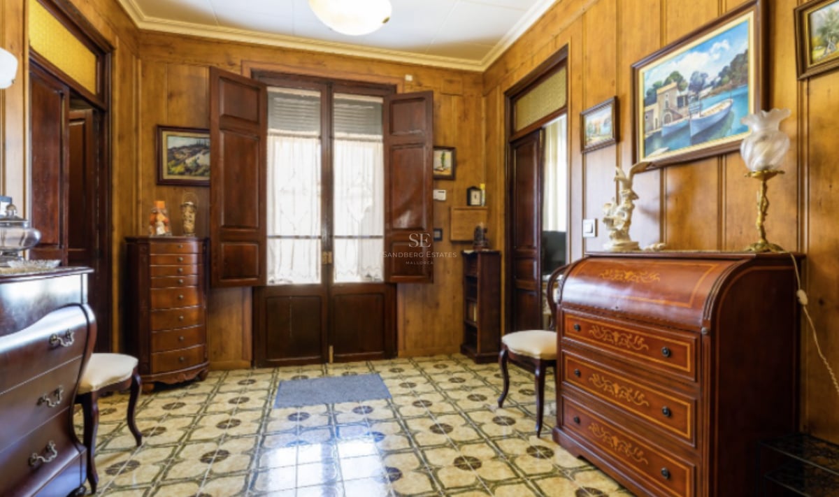 Hall d'entrée avec murs en bois, sol en carreaux décoratifs et meubles anciens classiques.