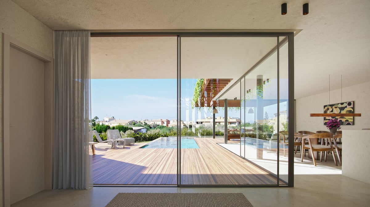 Vue depuis le salon à travers de grandes baies vitrées vers une terrasse en bois avec piscine et chaises longues.