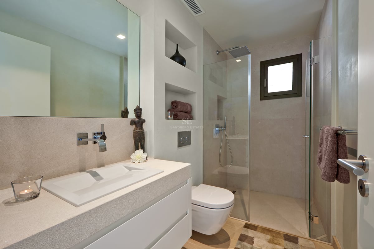 Salle de bain moderne avec vasque en pierre, WC suspendu et douche à l'italienne vitrée.