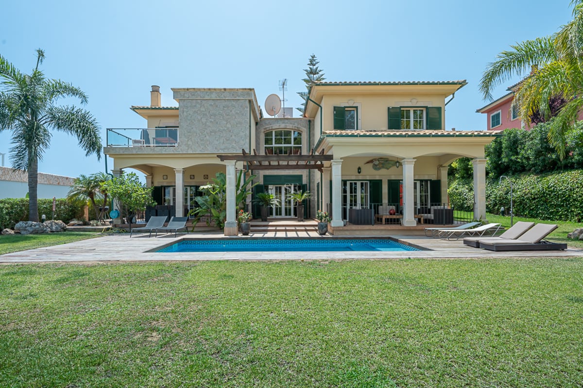 Villa méditerranéenne jaune avec piscine, volets verts, grand jardin et terrasses couvertes par temps clair.