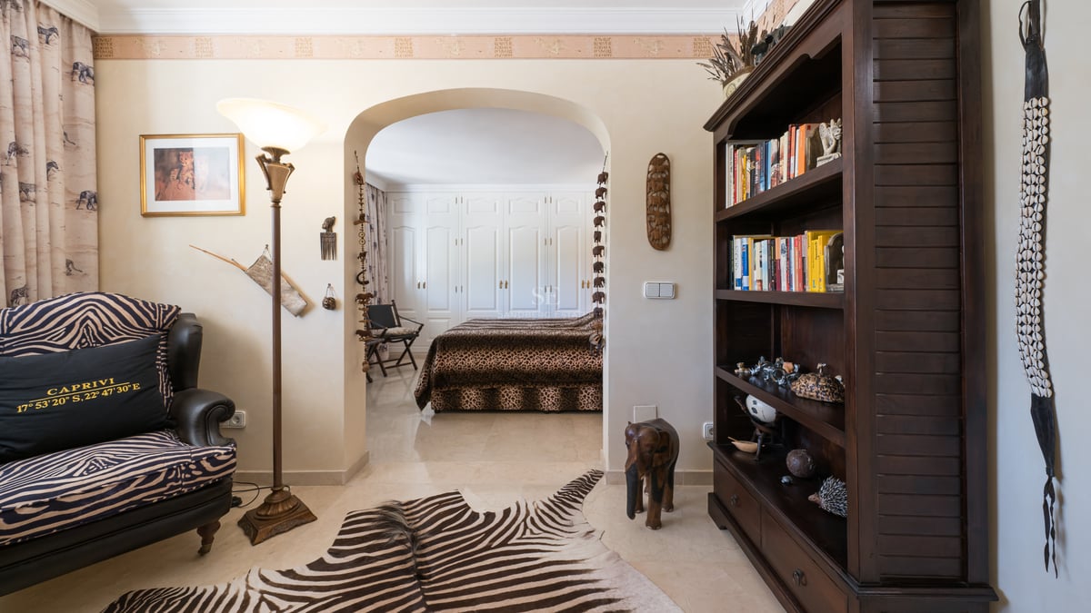 Salon à thème africain avec tapis en peau de zèbre menant à une chambre avec édredon léopard.