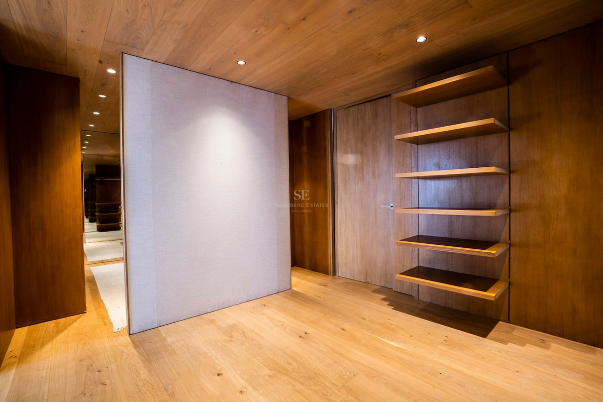 Dressing minimaliste avec murs et plafond en chêne naturel, étagères intégrées et éclairage chaleureux.