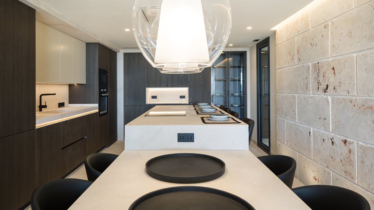 Cuisine contemporaine avec îlot en pierre, armoires en bois sombre et mur en pierre naturelle texturée.
