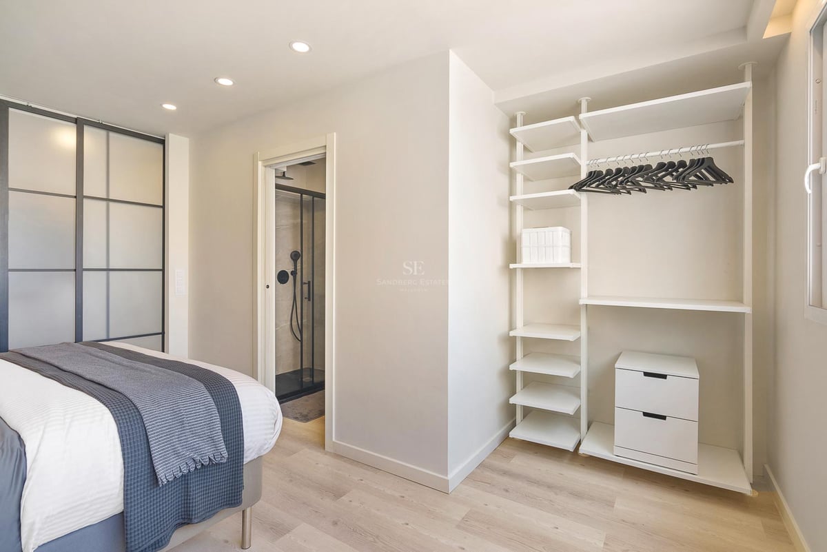 Chambre contemporaine lumineuse avec système de dressing blanc, parquet clair et aperçu de la salle de bain attenante.