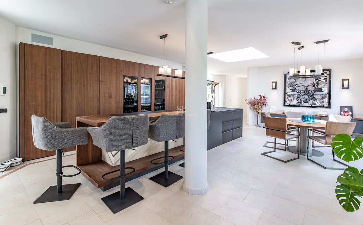 Cuisine moderne ouverte avec bar en bois, îlot gris, caves à vin et espace salle à manger contemporain.