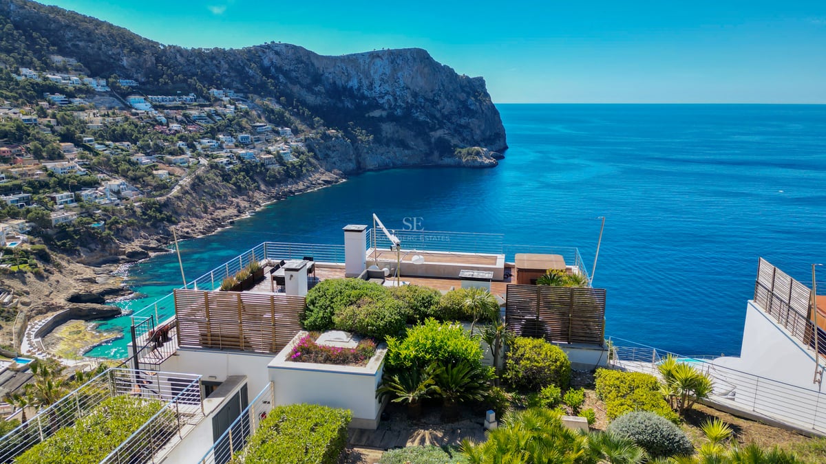 Terrasse contemporaine avec garde-corps en verre surplombant la mer et des falaises escarpées.