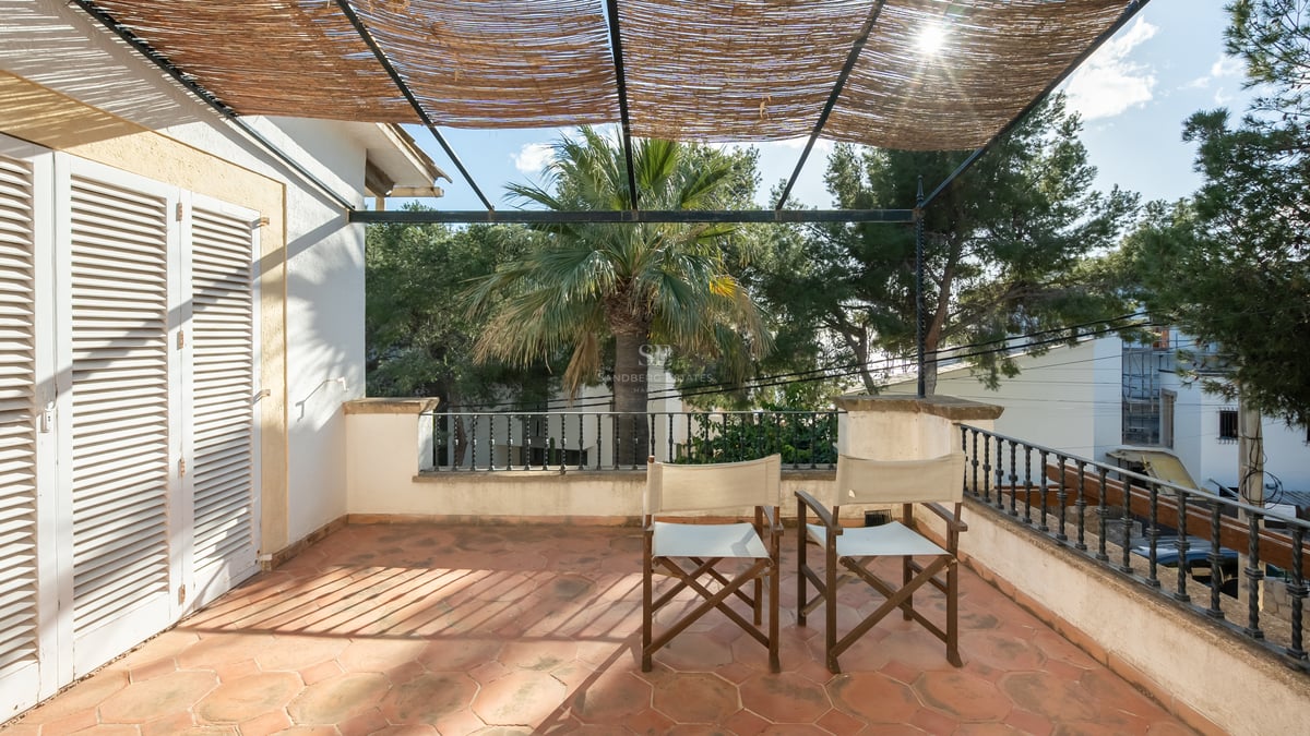 Terrasse ensoleillée avec carrelage en terre cuite, chaises de metteur en scène et pergola en canisse.