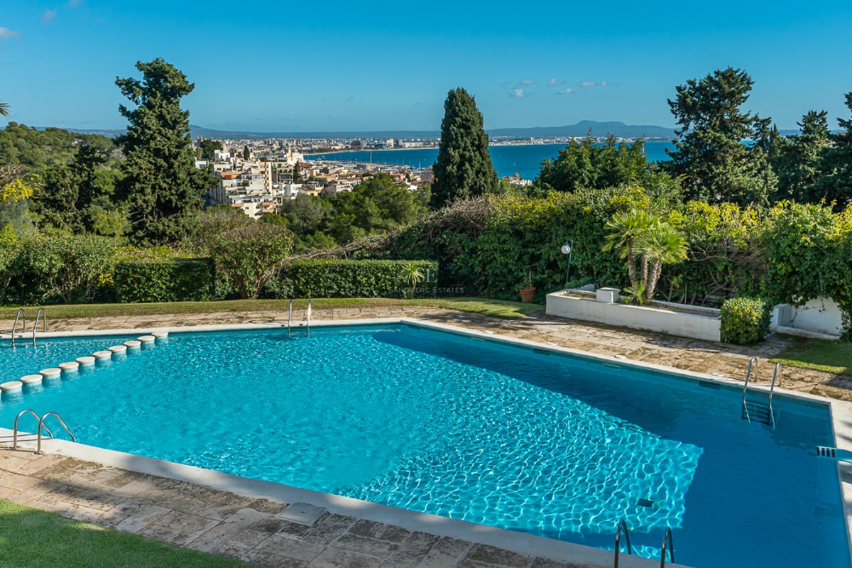 Vaste terrasse avec vue sur la mer. Mobilier moderne, piscine à débordement, rambarde en verre et élégants transats.