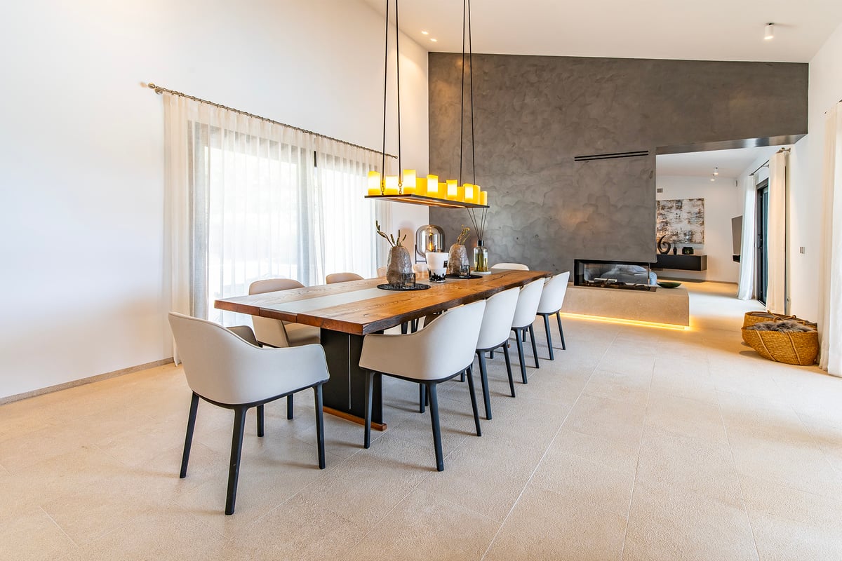 Vue d'une villa moderne avec piscine réfléchissante. Design minimaliste, grandes baies vitrées, environnement naturel luxuriant et ciel dégagé.