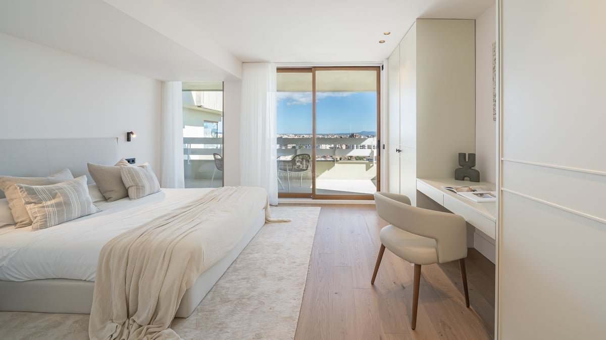 Chambre lumineuse avec parquet en chêne, bureau intégré et baies vitrées ouvrant sur une terrasse ensoleillée.
