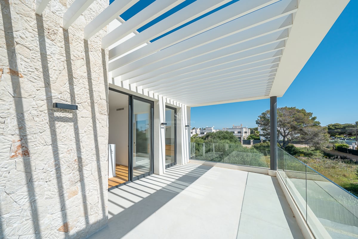 Terrasse ensoleillée avec pergola à lames blanches projetant des ombres sur un mur en pierre et garde-corps en verre.