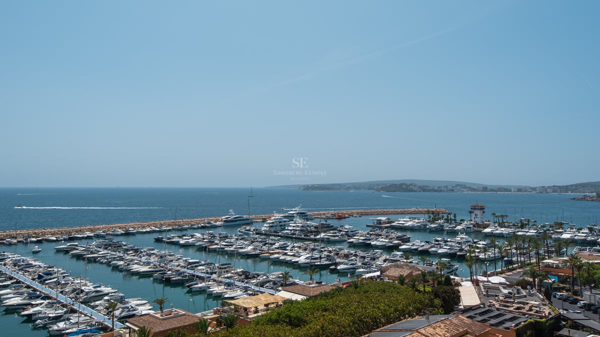 Vue en plongée d'une marina remplie de yachts blancs et de bateaux sous un ciel bleu azur.