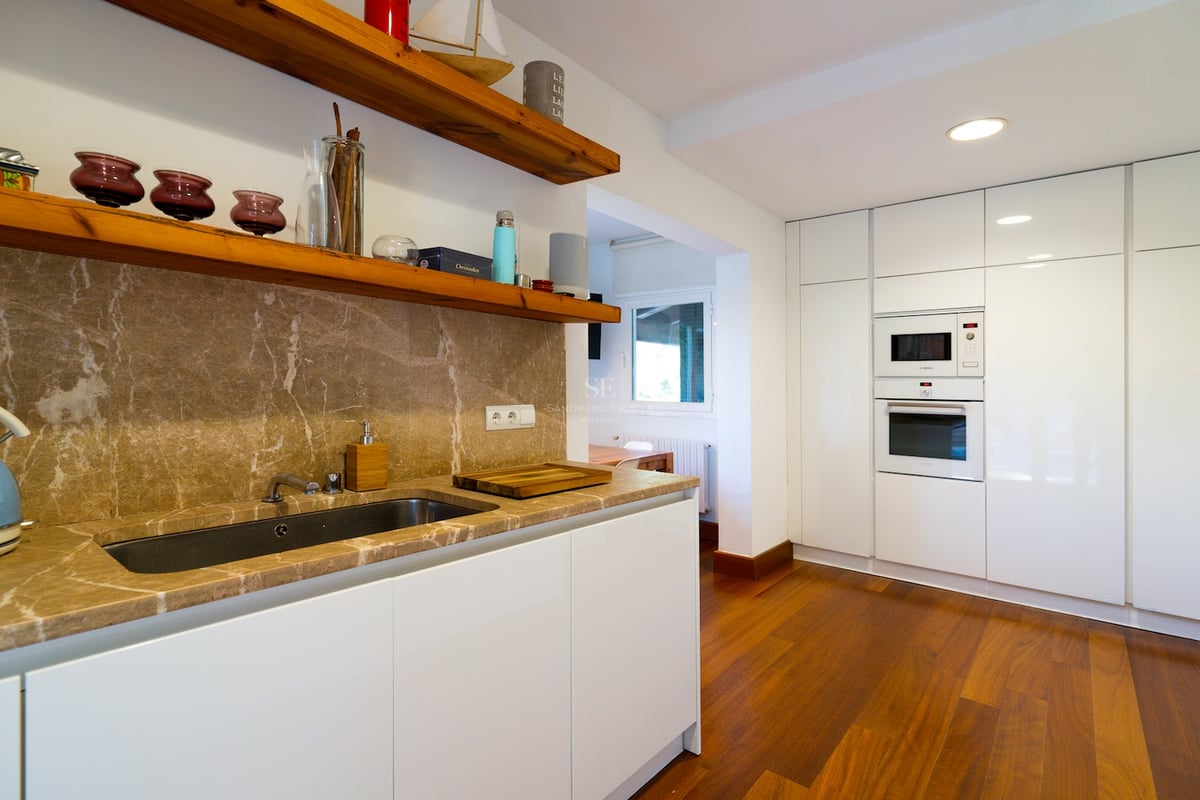 Cuisine blanche contemporaine avec plans de travail en marbre brun, étagères en bois et appareils intégrés.