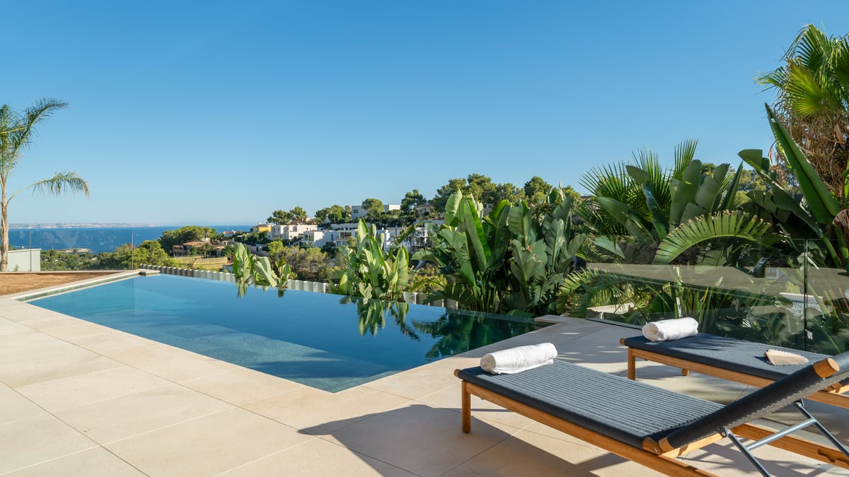 Vaste espace extérieur avec piscine, pelouse soignée, chaises longues et végétation luxuriante. Idéal pour la détente et les loisirs.