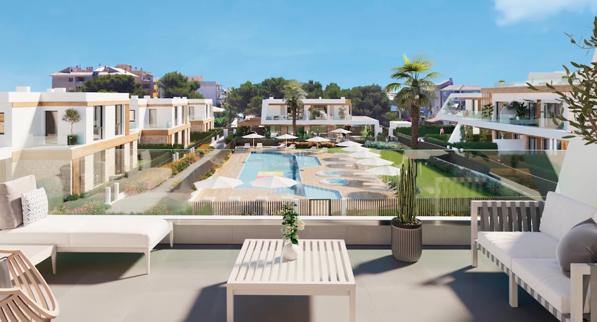 Modern terrace with white lounge furniture overlooking a large resort pool and manicured Mediterranean gardens.