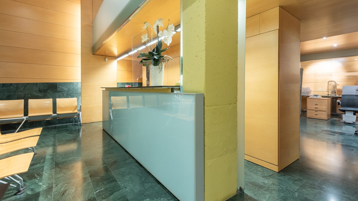 Modern lobby featuring a frosted glass reception desk, green marble floors, and light wood wall panels.