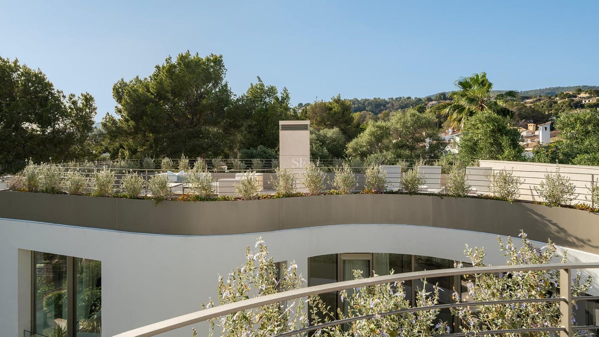 Toit-terrasse moderne aux lignes courbes avec garde-corps en verre, jardinières et mobilier de détente face aux montagnes.