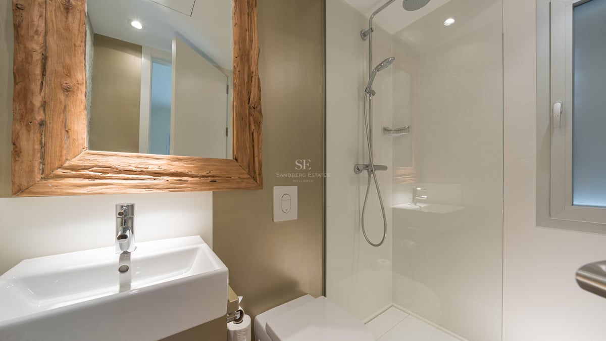 Salle de bain moderne avec douche à l'italienne en verre, lavabo blanc et miroir avec cadre en bois brut.