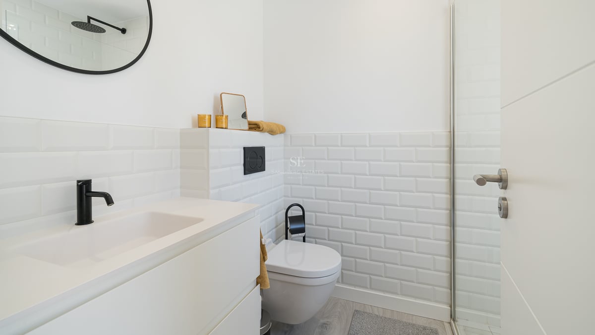 Salle de bain moderne avec carrelage métro blanc, robinetterie noire et lavabo minimaliste.