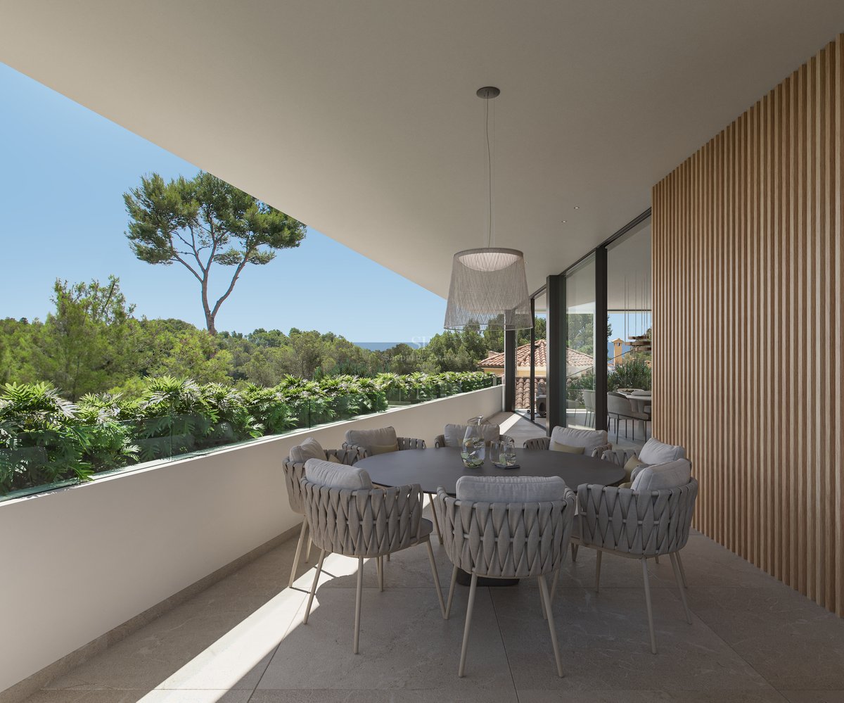Terrasse moderne avec table ronde, chaises tressées, mur en lattes de bois et vue sur la forêt et la mer.
