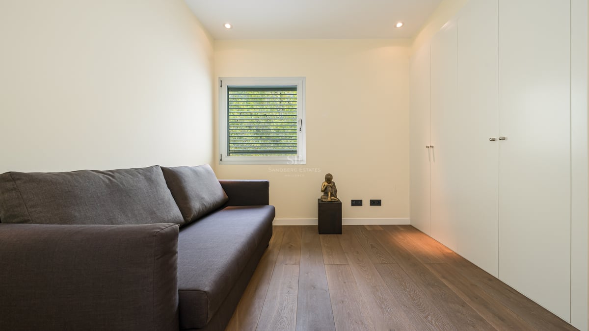 Chambre d'amis contemporaine avec canapé gris, parquet en chêne clair et grands placards intégrés blancs.