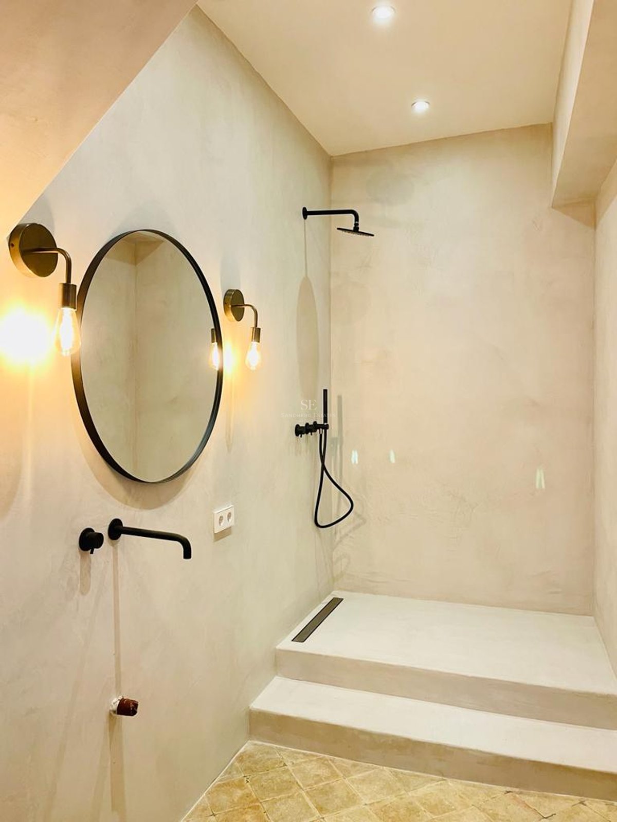Douche à l'italienne moderne en microciment avec robinetterie noir mat et miroirs design.