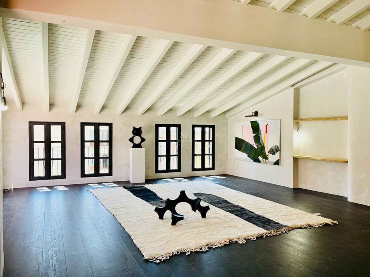 Pièce minimaliste avec parquet en bois foncé, plafond à poutres blanches et fenêtres à cadres noirs.