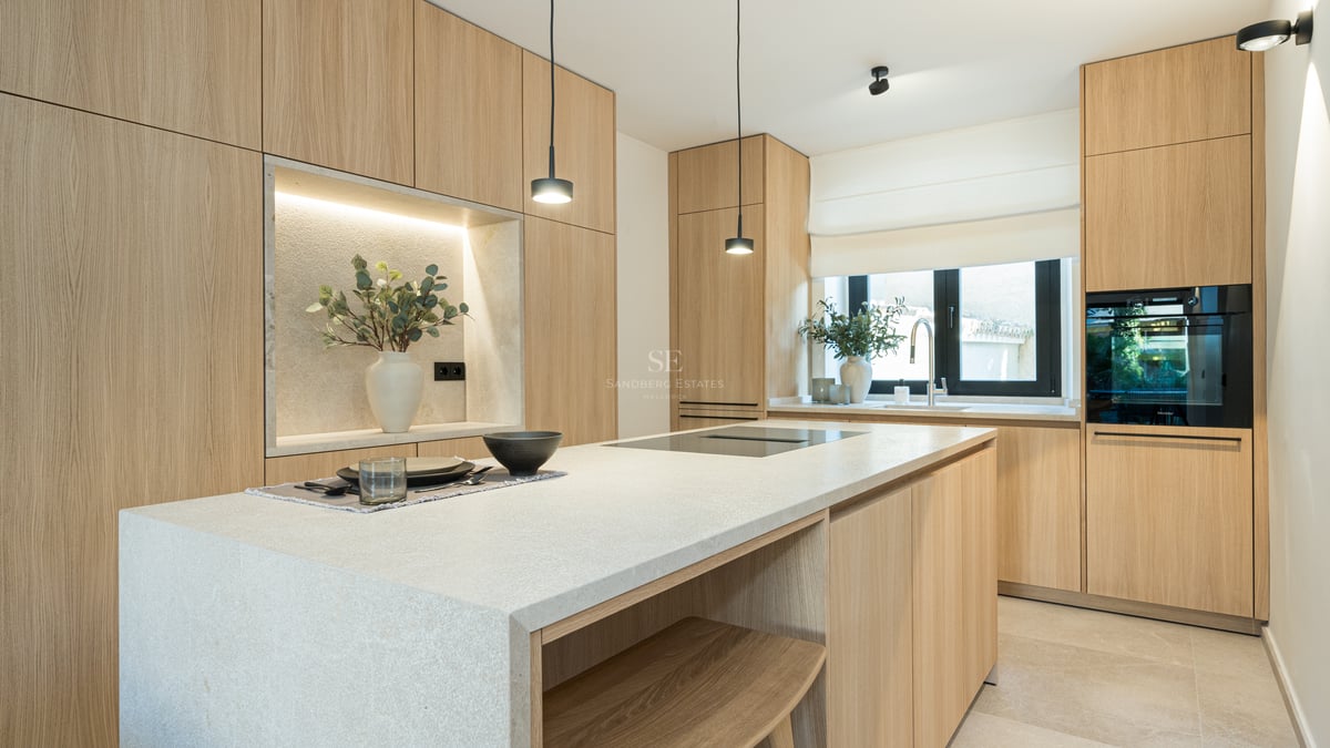 Cuisine moderne avec placards en chêne clair, grand îlot en pierre avec plaque à induction et appareils intégrés.