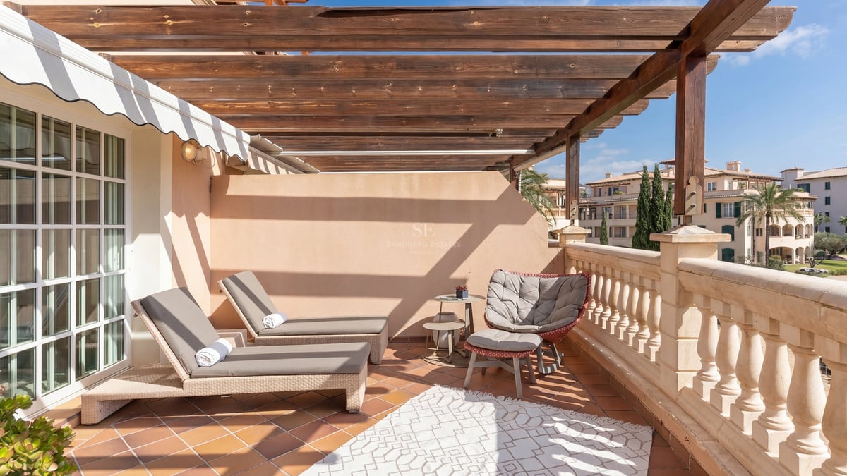 Terrasse ensoleillée avec pergola en bois, bains de soleil et sol en terre cuite.