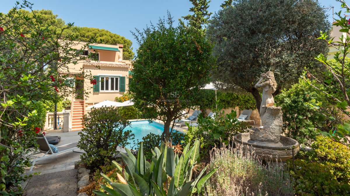 Piscine privée entourée de jardins méditerranéens, une statue classique et une villa aux tons terre cuite.
