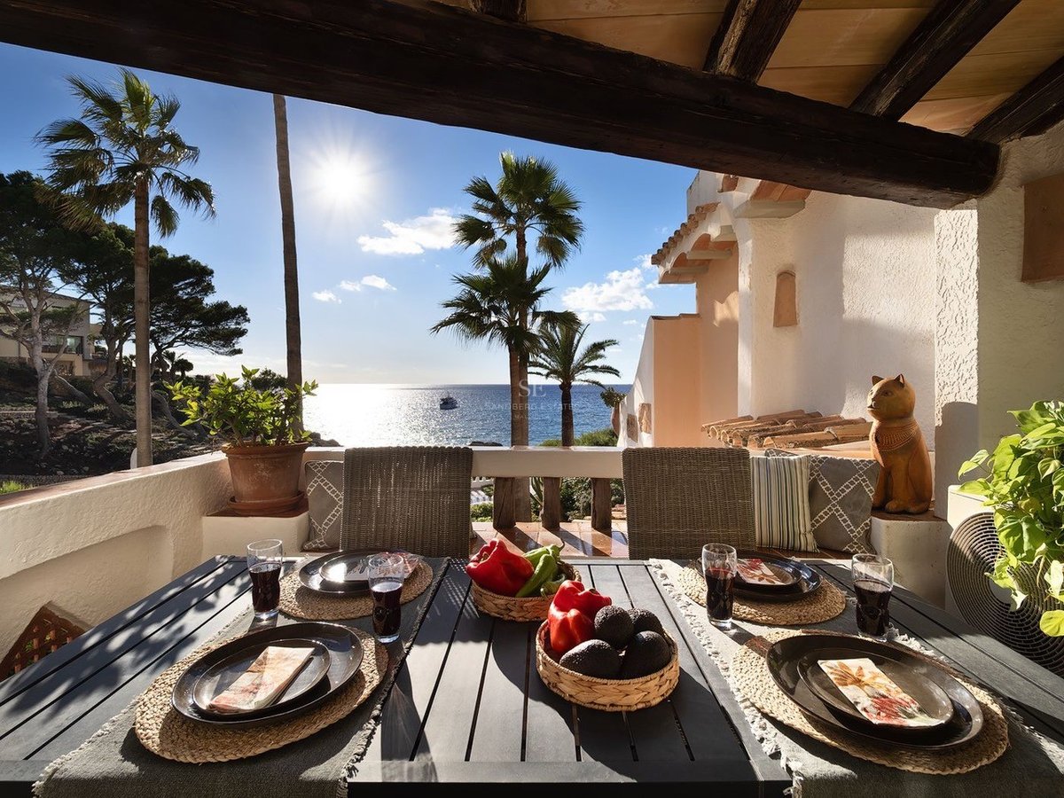 Table à manger extérieure dressée sur une terrasse ensoleillée surplombant la mer Méditerranée et des palmiers.