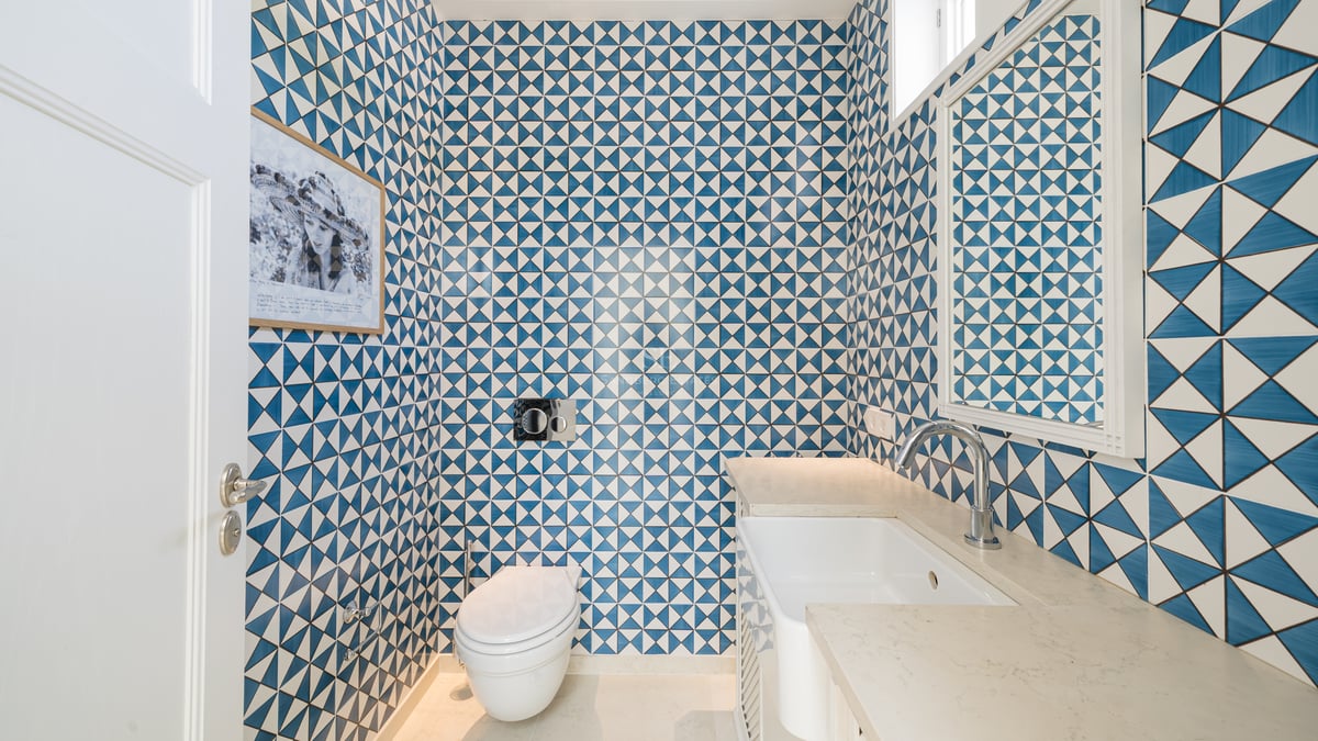 Petite salle de bain avec carreaux géométriques bleu et blanc, toilette moderne et vasque blanche.