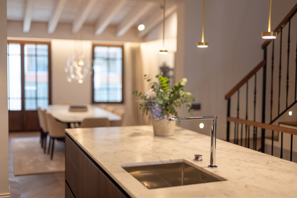 Îlot de cuisine moderne avec comptoir en marbre blanc, robinet chromé et évier intégré, face à la salle à manger.
