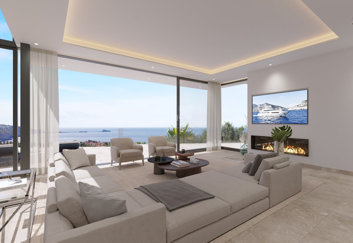 Salon contemporain avec grand canapé beige, cheminée linéaire et baies vitrées donnant sur la mer Méditerranée.