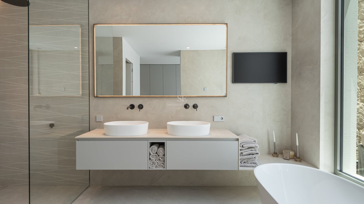 Salle de bains moderne avec double vasque suspendue, miroir rétroéclairé, robinetterie noir mat et baignoire îlot.