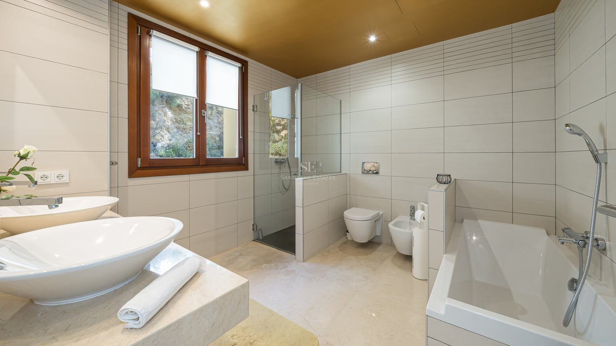 Salle de bains spacieuse avec double vasque, baignoire, douche à l'italienne et finitions en marbre beige.