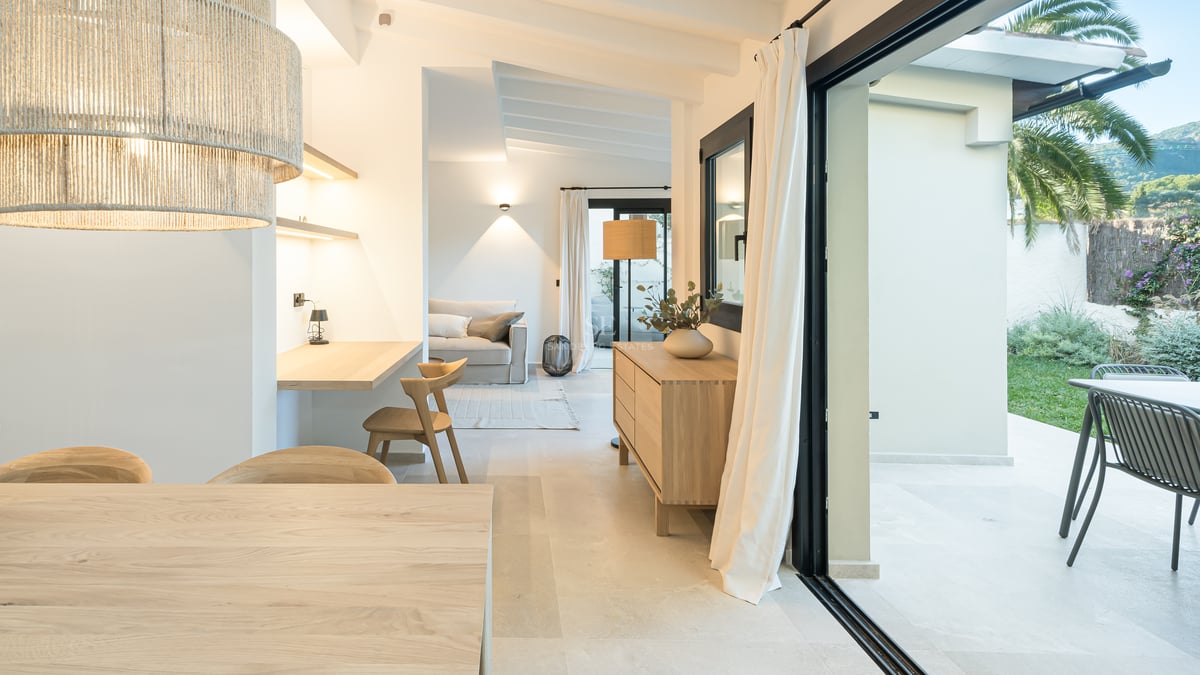 Salon contemporain en chêne clair avec coin bureau et larges baies vitrées ouvrant sur une terrasse ensoleillée.