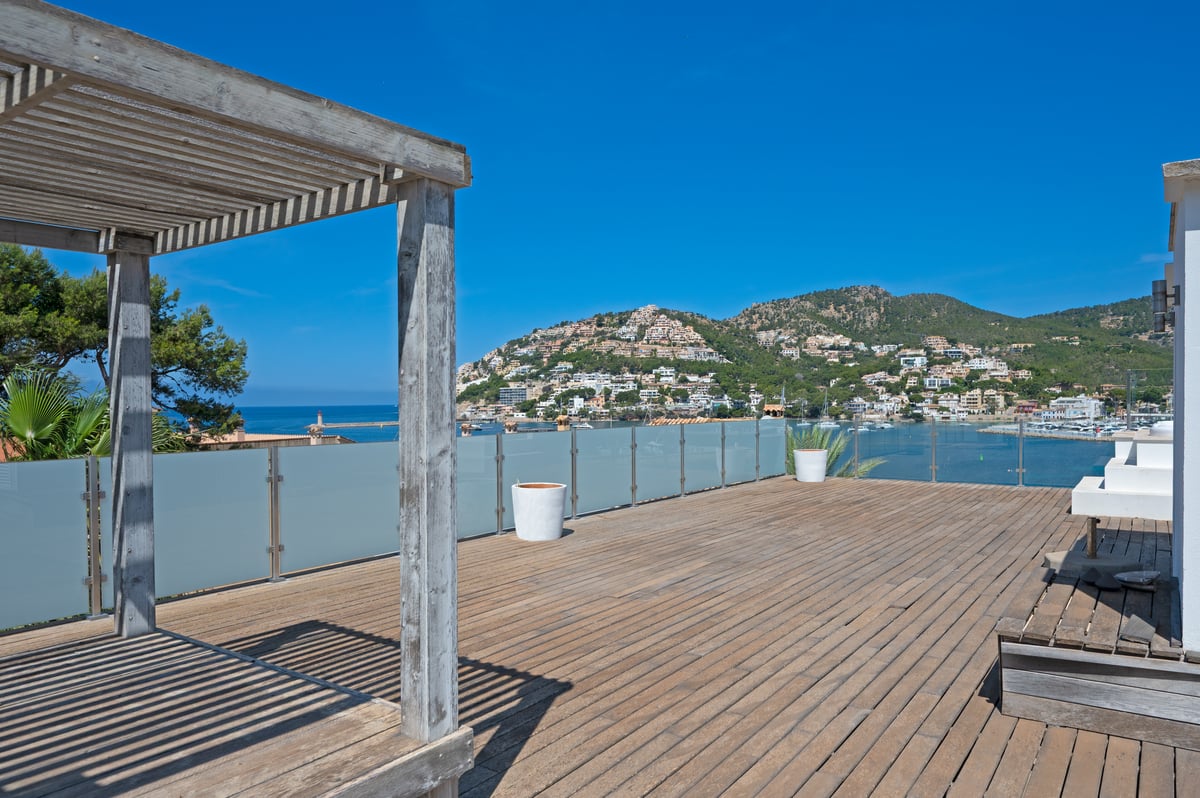 Grande terrasse en bois sur le toit avec pergola offrant une vue sur le port méditerranéen et les collines environnantes.