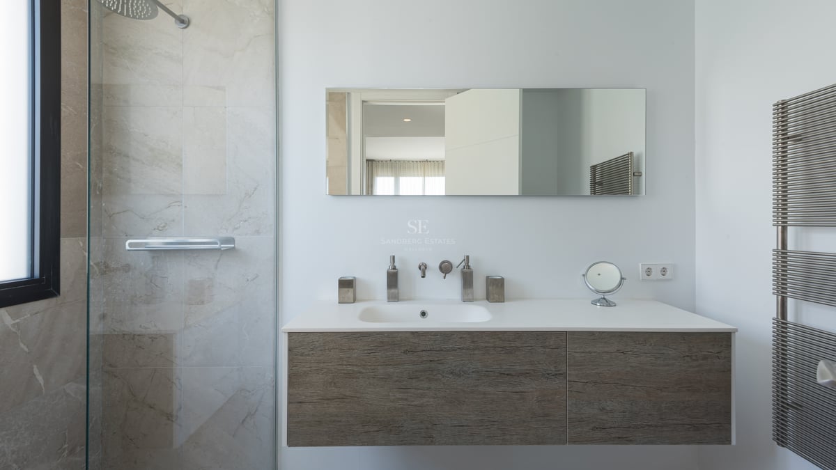 Salle de bains moderne avec meuble vasque suspendu en bois, paroi de douche en verre et finitions chromées.