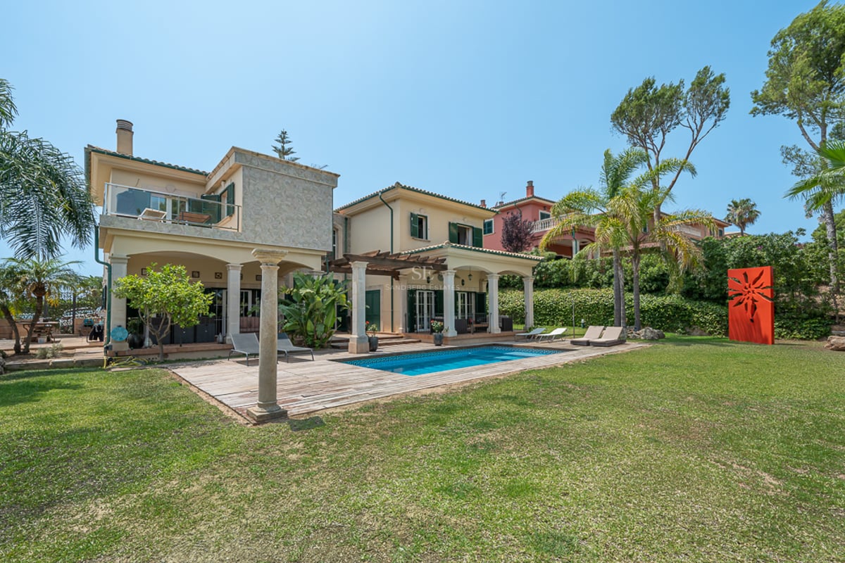 Extérieur de villa de luxe avec piscine, terrasse en bois, grand jardin et architecture méditerranéenne traditionnelle.