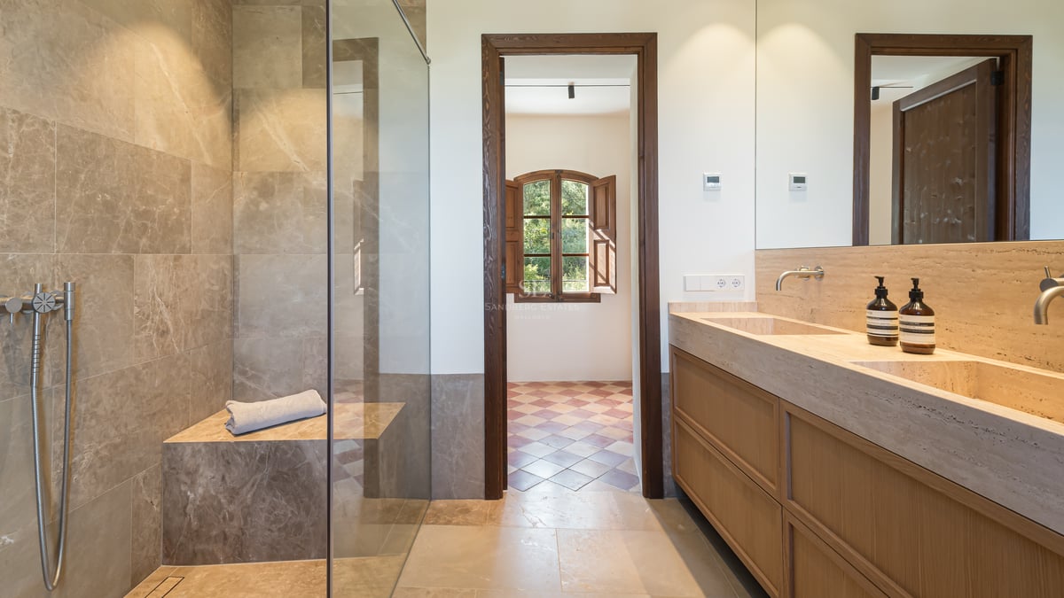 Salle de bains de luxe avec douche à l'italienne en pierre, double vasque intégrée et menuiserie en chêne.