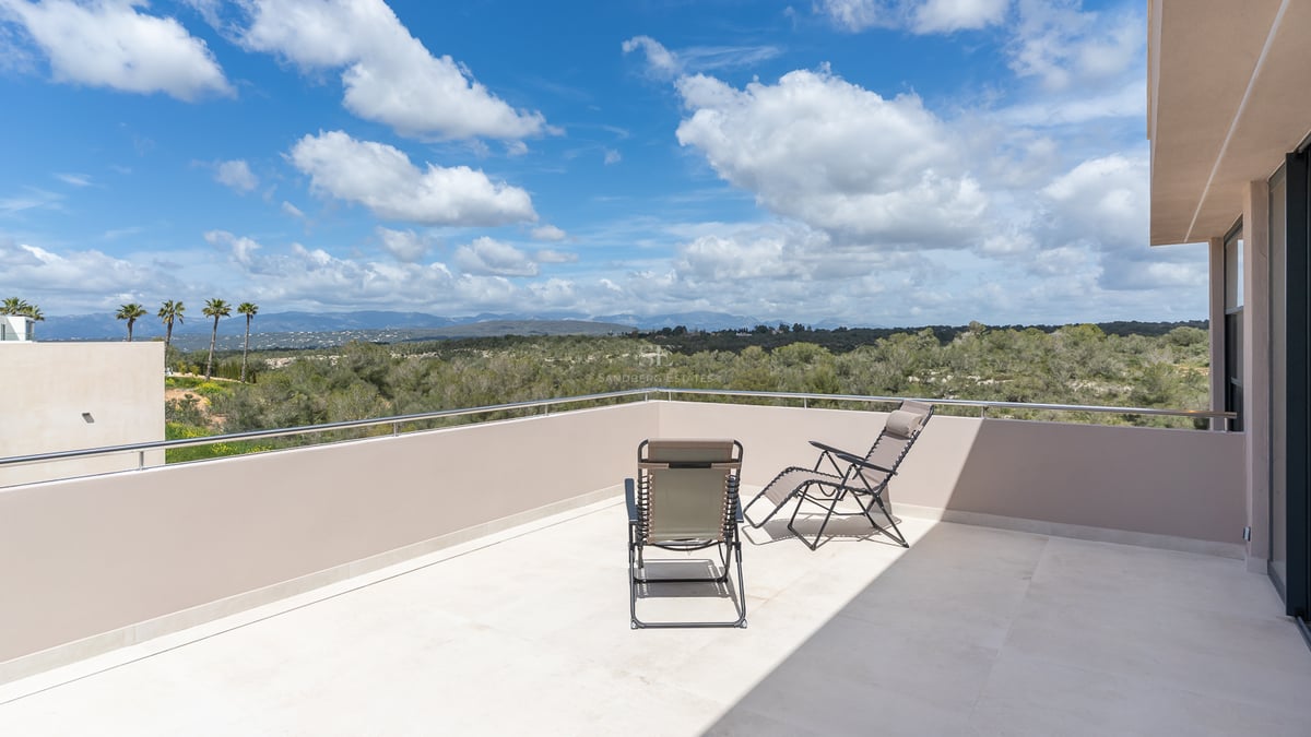 Toit-terrasse avec deux chaises longues offrant une vue sur une vallée verdoyante et des montagnes lointaines.