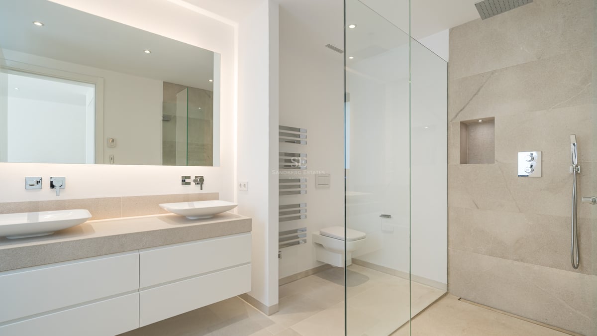 Salle de bain moderne avec double vasque, miroir rétroéclairé et douche à l'italienne avec carreaux en pierre.