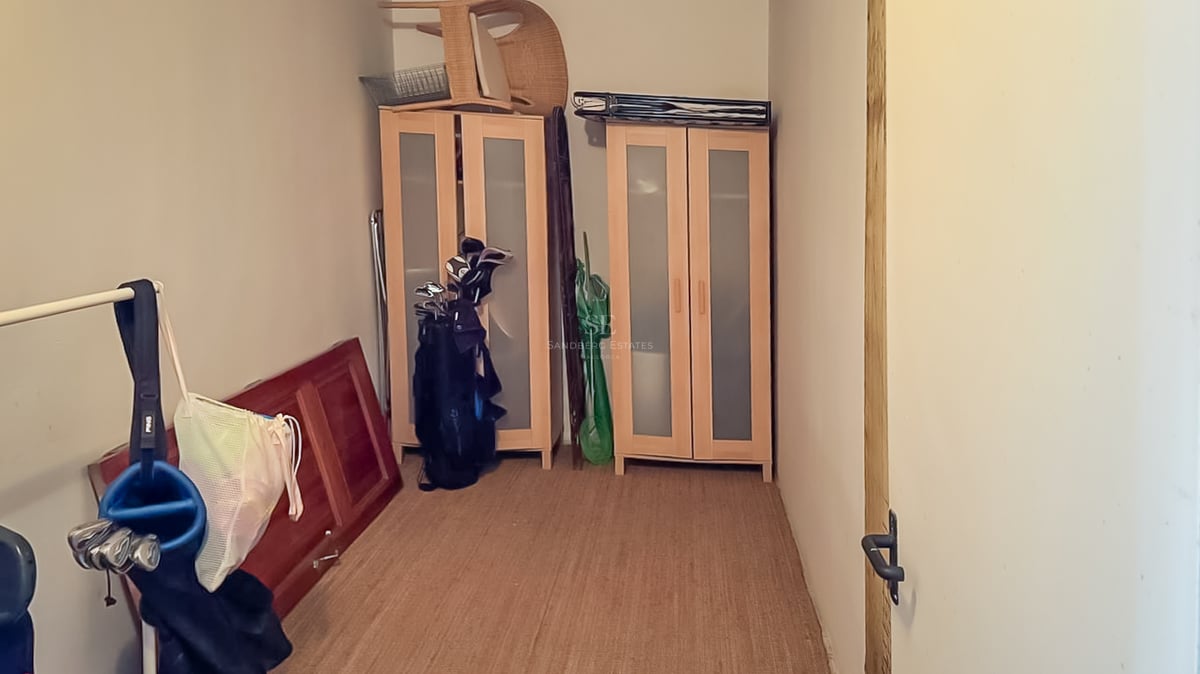 Vue intérieure d'un débarras avec des armoires en bois, des sacs de golf et un tapis en sisal.