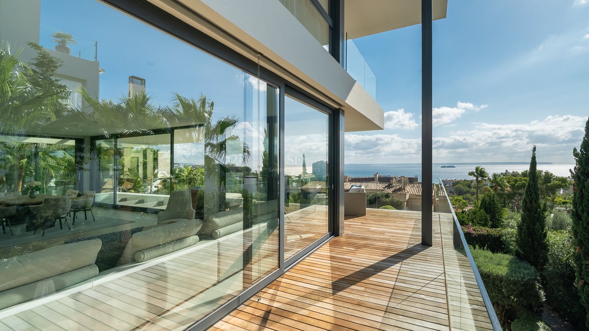 Terrasse moderne en bois avec garde-corps en verre offrant une vue panoramique sur la mer Méditerranée.