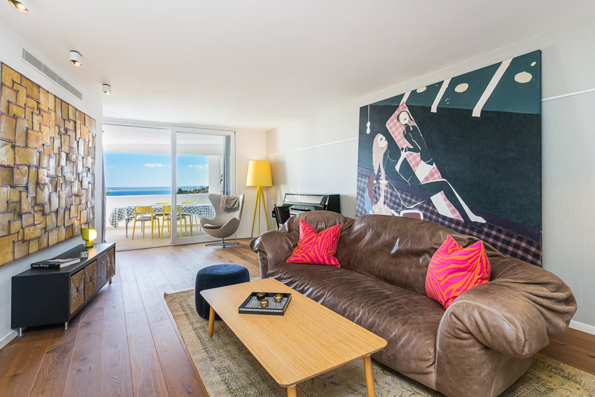 Intérieur lumineux avec balcon et vue sur la mer. Design moderne avec parquet et mobilier élégant. De grandes fenêtres maximisent la lumière naturelle.